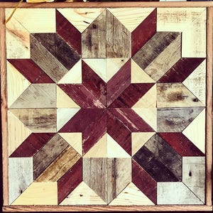 Puede incluir: Una pieza de arte de pared de madera con un patr&oacute;n geom&eacute;trico de madera roja, marr&oacute;n y beige. La madera est&aacute; dispuesta en un patr&oacute;n de estrella.