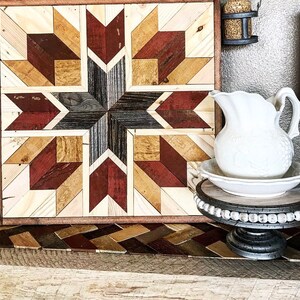 May include: A wooden wall art piece with a geometric pattern in shades of brown, red, and white. The art is framed and has a rustic look.