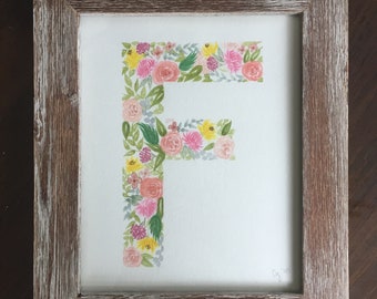 May include: A framed watercolour painting of the letter F made up of pink, yellow, and green flowers. The frame is a light brown wood with a distressed finish.