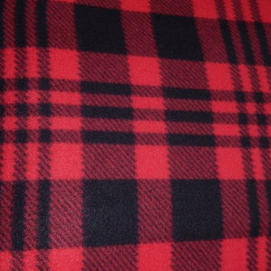 Op de afbeelding: Close-up van een rood en zwart geruite stof. Het patroon heeft grote, gelijkmatig verdeelde vierkanten en rechthoeken in een klassiek buffelruitontwerp. De stof heeft een zacht, getextureerd uiterlijk.