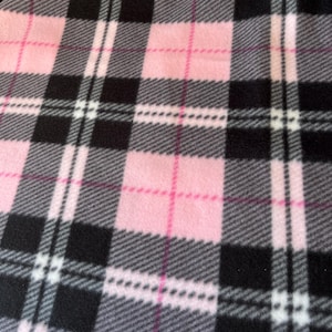 Op de afbeelding: Roze, zwart en wit geruit fleece-stof. De stof heeft een zachte, pluche textuur.