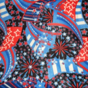 Op de afbeelding: Rode, witte en blauwe stof met een patroon van sterren, vuurwerk en strepen. De stof is perfect voor knutselprojecten, quilten of het maken van patriottische kleding.