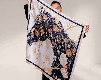 May include: A white silk scarf with a black horse design and floral accents. The scarf features a gold and black floral pattern and the text "Danelis" in the bottom right corner.