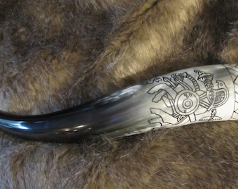 May include: A black and white drinking horn with a Viking warrior design etched into the side. The horn is made of polished bone and has a dark brown finish.