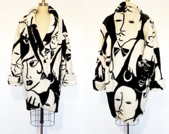 Peut inclure: Un manteau à manches longues arborant un imprimé graphique noir et blanc audacieux représentant des visages humains stylisés. Le manteau présente un large col châle, des manches à revers et une coupe décontractée, présenté sur un mannequin.