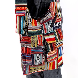 Puede incluir: Un bolso de hombro de patchwork colorido con una variedad de patrones tejidos en rojo, azul, verde y amarillo. El bolso tiene un bolsillo con cremallera y un cierre de solapa.