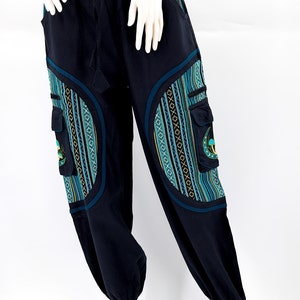May include: Black pants with a drawstring waist and blue and green patterned pockets. The pockets have a circular design with a geometric pattern.