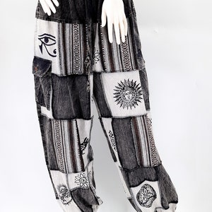 Könnte beinhalten: Schwarz-weiße Patchwork-Hose mit verschiedenen Designs, darunter eine Sonne, ein Auge und andere geometrische Muster.