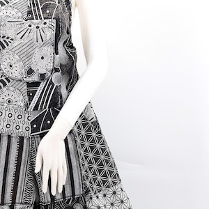 Może przedstawiać: Czarno-biały kombinezon w stylu patchwork z geometrycznym wzorem. Kombinezon ma szerokie nogawki i bezrękawny krój.