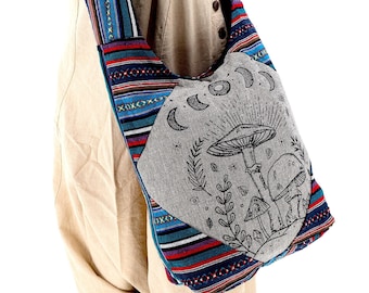May include: A gray and blue striped canvas shoulder bag with a gray pocket featuring a black and white illustration of mushrooms and moons. The bag has a long strap with a blue, red, and white striped pattern.