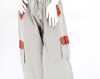 May include: Beige linen pants with colorful embroidered patches on the pockets. The pants have a drawstring waist and a relaxed fit.