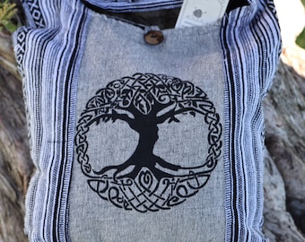 May include: A gray canvas tote bag with black and white striped trim. The bag features a black tree of life design with a Celtic knot border.