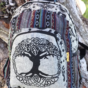 May include: A gray backpack with a black Tree of Life design on the front pocket. The backpack has a patterned design with red, blue, and green stripes. The bag has black zippers and straps, and a small yellow tag.