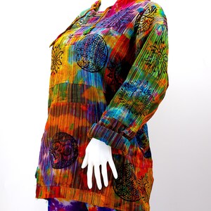 K&ouml;nnte beinhalten: Ein farbenfrohes, tie-dye-Shirt mit langen &Auml;rmeln und Knopfleiste. Das Shirt zeigt verschiedene Muster, darunter Sonnen, Blumen und geometrische Designs. Das Shirt ist aus einem weichen, leichten Stoff gefertigt und perfekt zum Schichten.