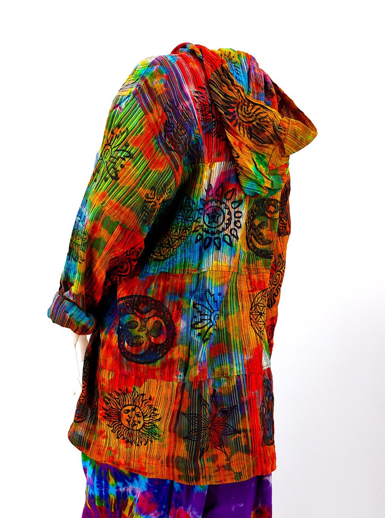 K&ouml;nnte beinhalten: Eine bunte Kapuzenjacke mit Batik-Mustern und schwarzen, gedruckten Symbolen, darunter Sonnen, Monde und Blumen.