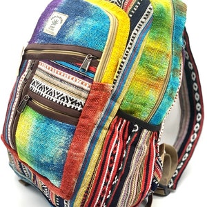 May include: A multi-colored backpack featuring a woven fabric with tie-dye patterns in blue, yellow, and red. It includes multiple zippered compartments, brown trim, and a rectangular label reading Himalayan Hemp Trade Made in Nepal.