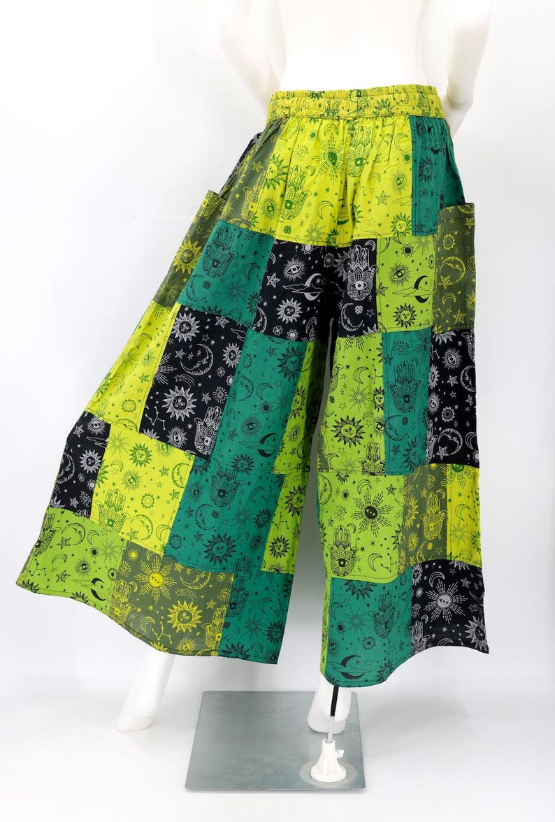 Puede incluir: Pantalones patchwork de pernera ancha en tonos verdes, negros y amarillos. La tela presenta dise&ntilde;os celestiales y de manos. Los pantalones tienen cintura el&aacute;stica y bolsillos.