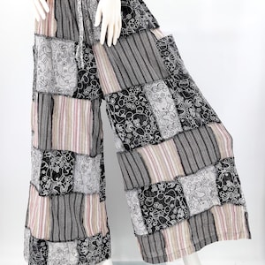 May include: Black and white patchwork wide-leg pants with a floral pattern. The pants have a drawstring waist and are made of a lightweight fabric.