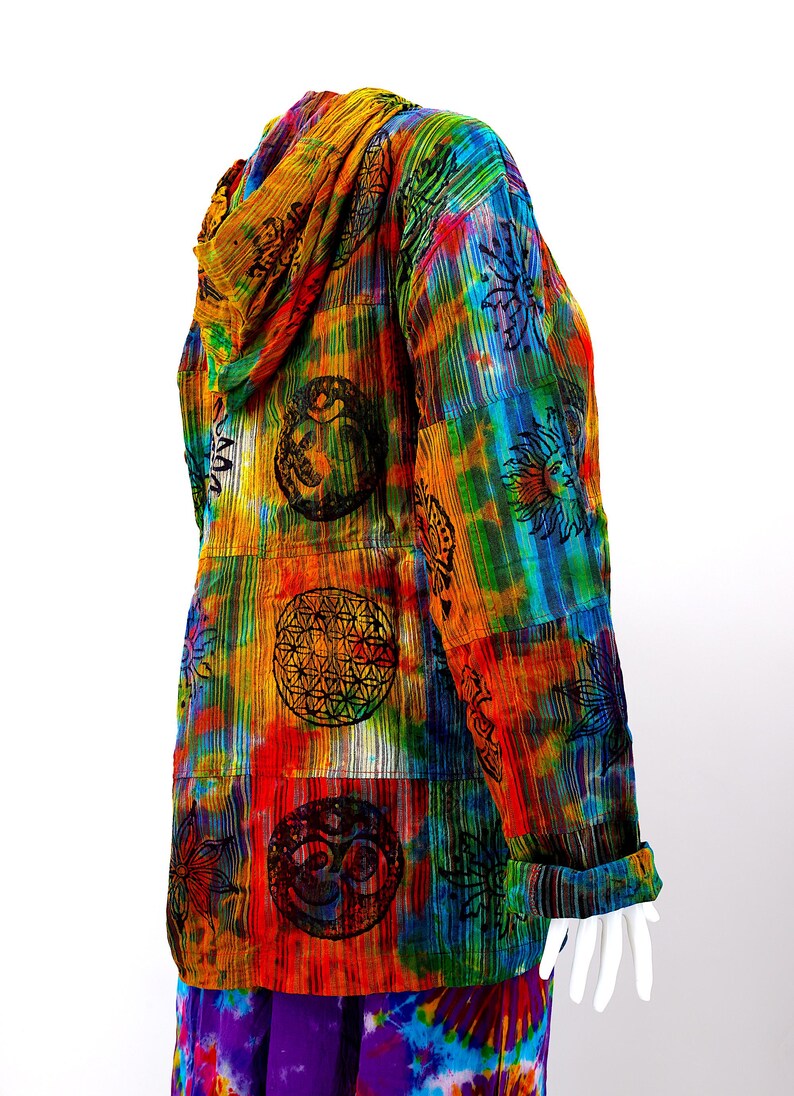 K&ouml;nnte beinhalten: Eine bunte Kapuzenjacke mit einem Batik-Muster und verschiedenen darauf gedruckten Symbolen. Die Jacke ist aus einem weichen, leichten Stoff gefertigt und hat eine lockere Passform.