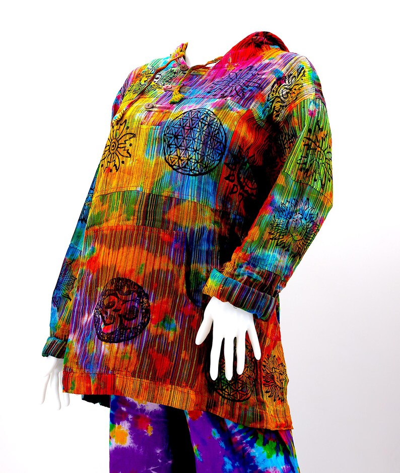 K&ouml;nnte beinhalten: Ein farbenfrohes Batik-Kapuzenoberteil mit Patchwork-Design, das verschiedene Symbole und Muster zeigt. Das Oberteil hat lange &Auml;rmel und eine lockere Passform.