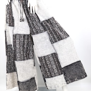 May include: Patchwork wide-leg pants in shades of gray, black, and white. The pants feature a drawstring waist and a mix of patterned and solid fabric panels. The design includes geometric and textured patterns.