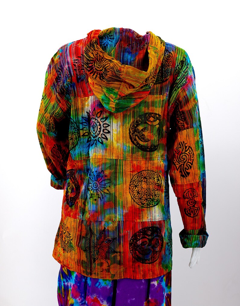 K&ouml;nnte beinhalten: Ein farbenfrohes Kapuzenhemd mit einem Batik-Muster und verschiedenen darauf gedruckten Symbolen. Die Symbole beinhalten eine Sonne, eine Blume und einen Kreis mit einem Stern darin. Das Hemd ist aus einem weichen, bequemen Stoff gefertigt und hat eine lockere Passform.