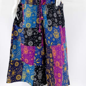 Puede incluir: Pantalones palazzo patchwork en tonos azules, morados, negros y amarillos. Los pantalones de pernera ancha presentan un estampado celestial y de mano de F&aacute;tima. La cintura tiene un cierre de cord&oacute;n. Los pantalones se exhiben en un maniqu&iacute;.