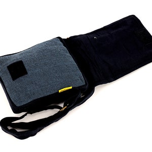 May include: A black and blue canvas messenger bag with a flap closure and an adjustable shoulder strap. The bag has a small pocket on the front and a larger pocket on the inside.