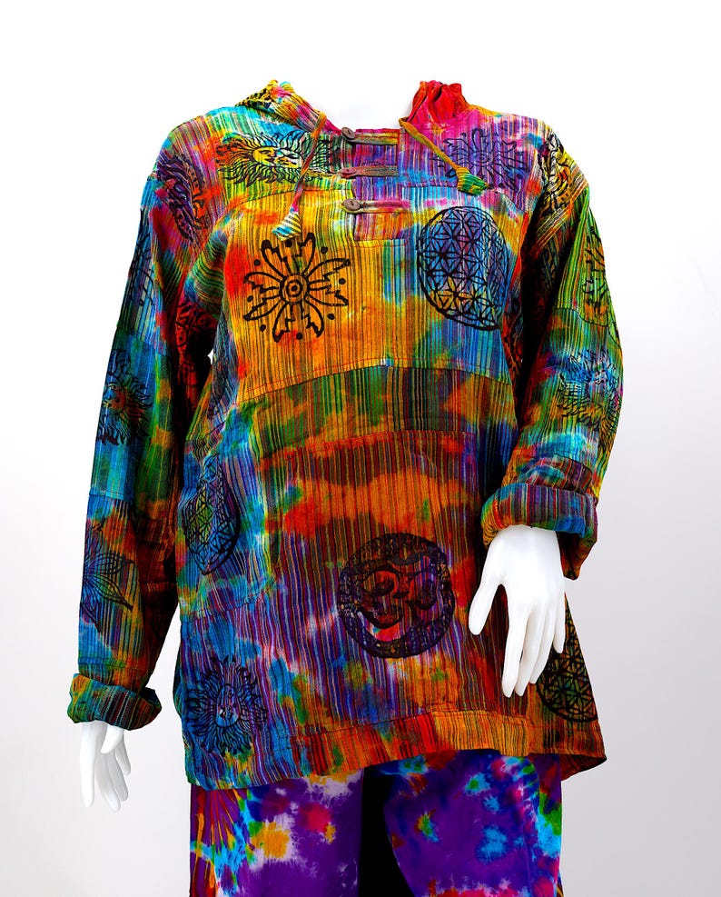 K&ouml;nnte beinhalten: Ein farbenfrohes Batik-Kapuzenoberteil mit langen &Auml;rmeln und verschiedenen gedruckten Symbolen, darunter eine Blume, eine Sonne und ein Mandala. Das Oberteil ist aus einem weichen, bequemen Stoff gefertigt und hat eine lockere Passform.