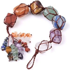 May include: A seven-stone chakra bracelet with a tassel. The stones are red, orange, yellow, green, blue, indigo, and violet. The bracelet is made of brown string and has a knotted design.