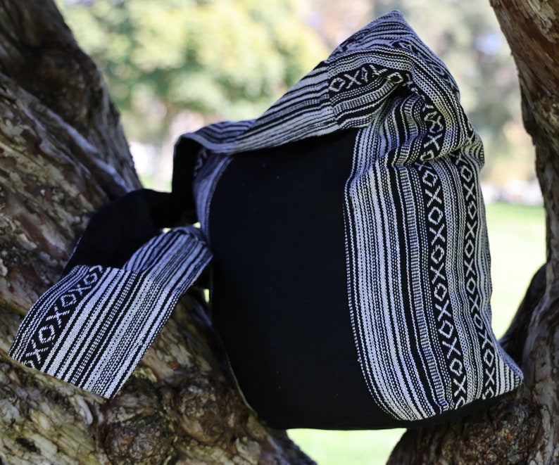 May include: Black and white striped tote bag with a woven design. The bag is made from a soft, durable fabric and has a spacious interior.