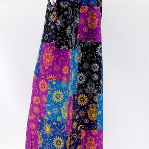 Puede incluir: Falda larga de patchwork con dise&ntilde;os celestiales y de mano de F&aacute;tima en morado, azul, negro y dorado. La falda tiene una cintura ancha y el&aacute;stica y una silueta fluida. La tela parece ligera. La falda mide unos 100 cm de largo.