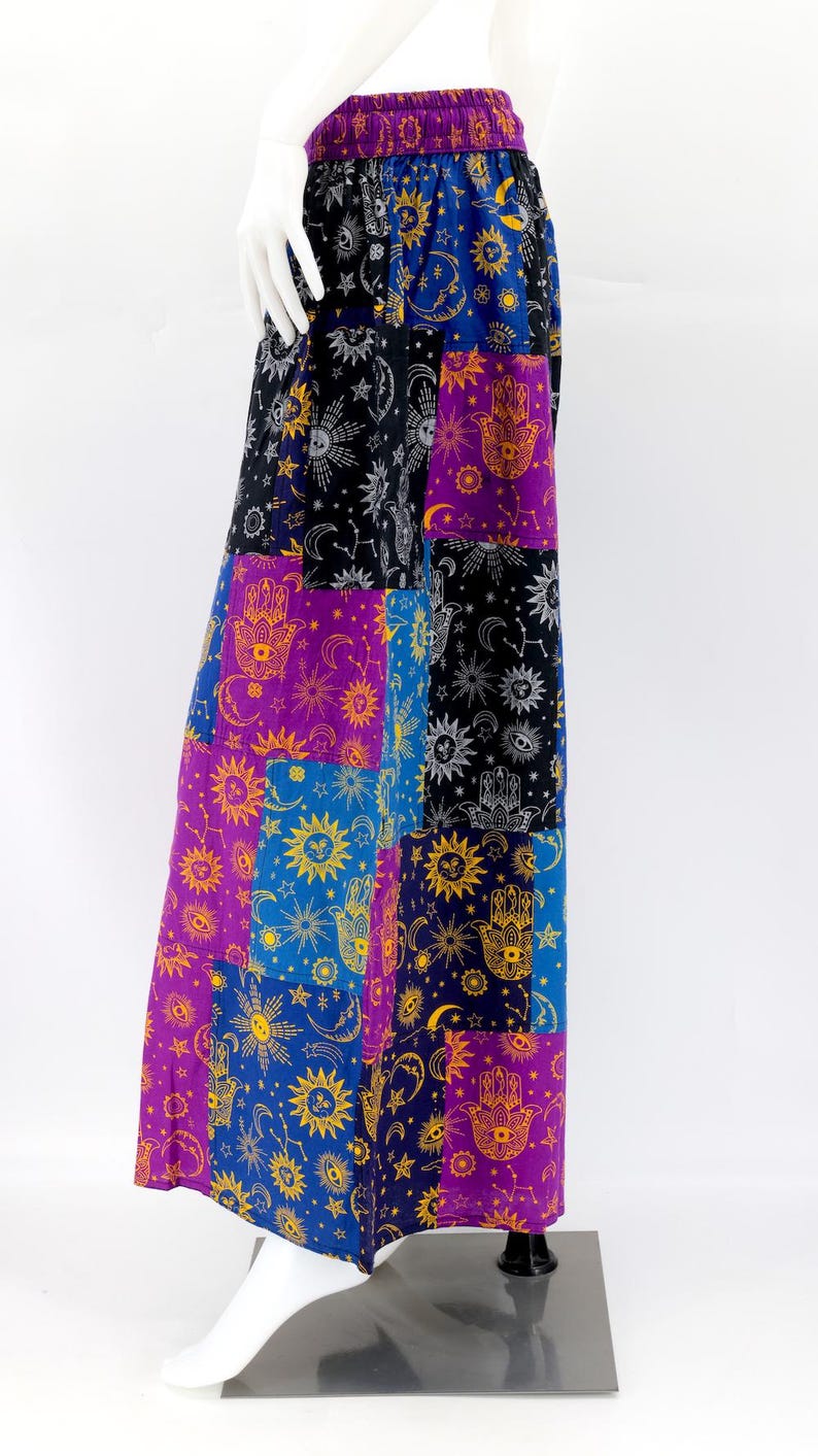 Puede incluir: Falda larga de patchwork con dise&ntilde;os celestiales y de mano de F&aacute;tima en morado, azul, negro y dorado. La falda tiene una cintura ancha y el&aacute;stica y una silueta fluida. La tela parece ligera. La falda mide unos 100 cm de largo.