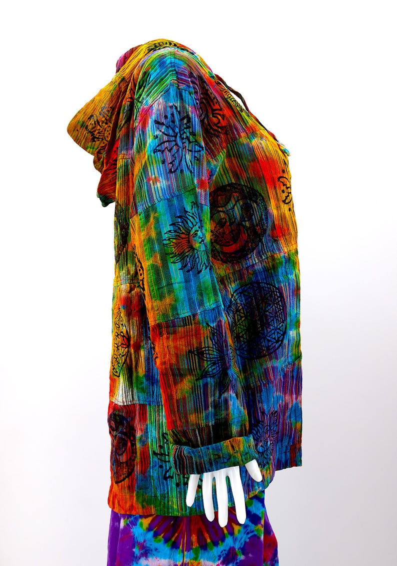 K&ouml;nnte beinhalten: Ein farbenfrohes Kapuzenhemd mit einem Batik-Muster und verschiedenen darauf gedruckten Symbolen. Das Hemd ist aus einem weichen, leichten Stoff gefertigt und hat eine lockere Passform.