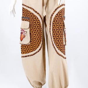 Puede incluir: Pantalones beige con patrones geométricos marrones y dorados y un gráfico de hongo en el bolsillo.