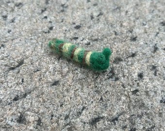 May include: A green and brown striped felt caterpillar toy with a green head.