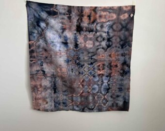 May include: A square fabric piece featuring a tie-dye pattern in shades of charcoal black, muted blue, and dusty rose. The design displays a complex, symmetrical arrangement of blurred, organic shapes and intricate lines across the entire surface.