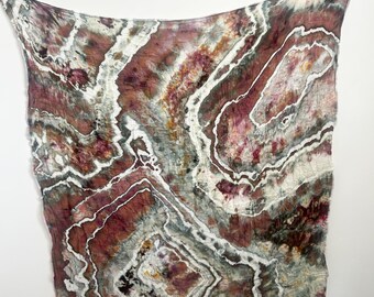 May include: A square textile featuring a geode-inspired pattern with swirling layers of deep burgundy, muted gray, and earthy brown tones. The design is defined by stark white, irregular lines that mimic crystalline structures across the fabric.