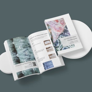 Könnte beinhalten: Ein geöffnetes Buch mit Anweisungen zum Falten von Stoff für Tie-Dye. Das Buch trägt den Titel "Tie-Dye-Falttechniken" und zeigt 11 Möglichkeiten, Stoff für wunderschönes Tie-Dye zu falten. Das Buch ist auf einer Seite mit dem Titel "Gerade abwechselnde Linien" mit einem QR-Code geöffnet.