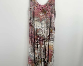 May include: A sleeveless dress featuring a high-low hemline and a V-neckline. The fabric displays an abstract tie-dye pattern in shades of dusty rose, muted purple, charcoal gray, and cream, creating a marbled effect across the entire garment.