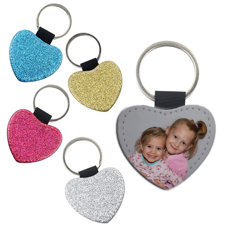 May include: Four heart-shaped keychains with different designs. One keychain is silver glitter, one is gold glitter, one is pink glitter, and one has a photo of two young girls.