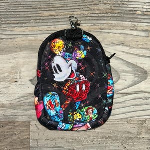 May include: A small black zippered pouch featuring a colourful all-over print of various animated characters, including a prominent white mouse head, surrounded by small multicoloured starbursts. The pouch includes a silver metal lobster clasp.