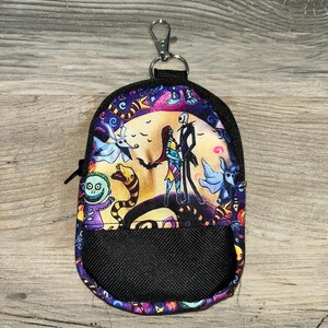May include: A small, rounded zipper pouch featuring a colorful print of characters from The Nightmare Before Christmas, including Jack Skellington and Sally. The pouch has a black mesh front pocket, black trim, and a silver metal lobster claw clasp.