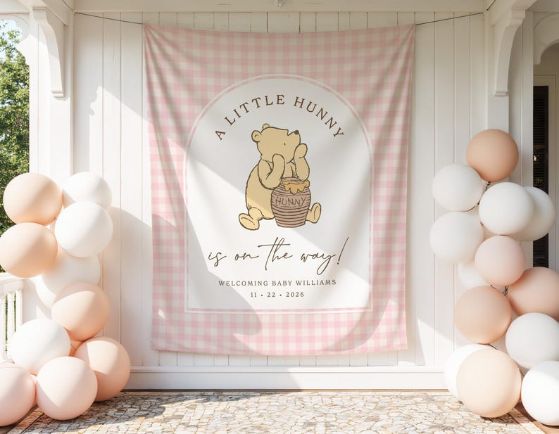May include: A rectangular fabric backdrop featuring a light pink and white gingham pattern with a central arch containing a cartoon bear holding a honey pot. Text reads A LITTLE HUNNY is on the way! WELCOMING BABY WILLIAMS 11 22 2026.