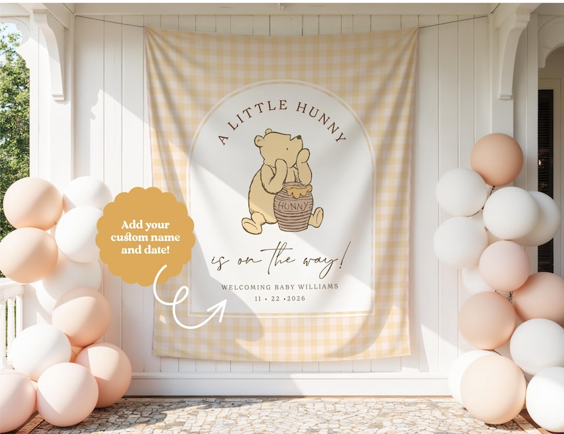 May include: A rectangular fabric backdrop featuring a light yellow gingham pattern with a central arch design. It displays a cartoon bear holding a honey pot, with the text A LITTLE HUNNY is on the way! WELCOMING BABY WILLIAMS 11 22 2026.