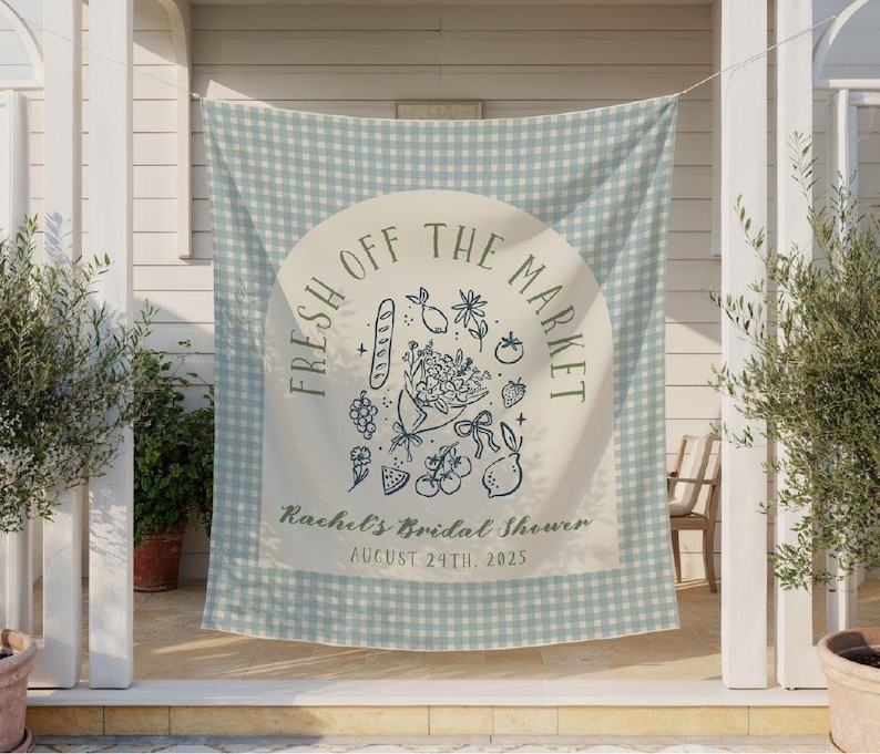 May include: A light blue and white gingham fabric banner with the text "FRESH OFF THE MARKET" in a circular design. Below the text is "Rachel's Bridal Shower" and the date "AUGUST 24TH, 2025". The banner has illustrations of fruits and flowers.