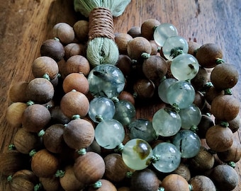 May include: A mala or prayer beads made of dark brown wood and green gemstone beads with a green tassel.