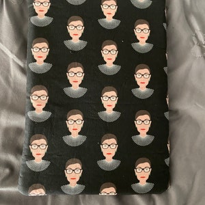 Könnte beinhalten: Schwarze Laptop-Hülle aus Stoff mit einem sich wiederholenden Muster einer Frau mit Brille und weißem Kragen.