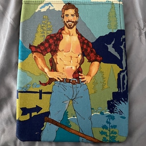 Könnte beinhalten: Eine blaue, grüne und gelbe Stofftasche mit einer Bergszene und einem Mann, der ein rot-schwarzes Karohemd, blaue Jeans und einen Bart trägt. Der Mann hält eine Axt.