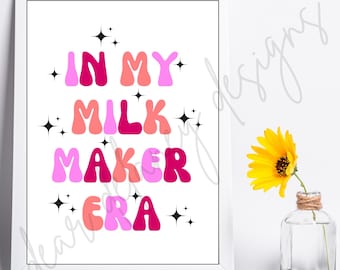 May include: A framed print with the words "IN MY MILK MAKER ERA" in pink, coral, and fuchsia bubble letters. Black starbursts accent the text. A yellow sunflower in a small glass vase is to the right.